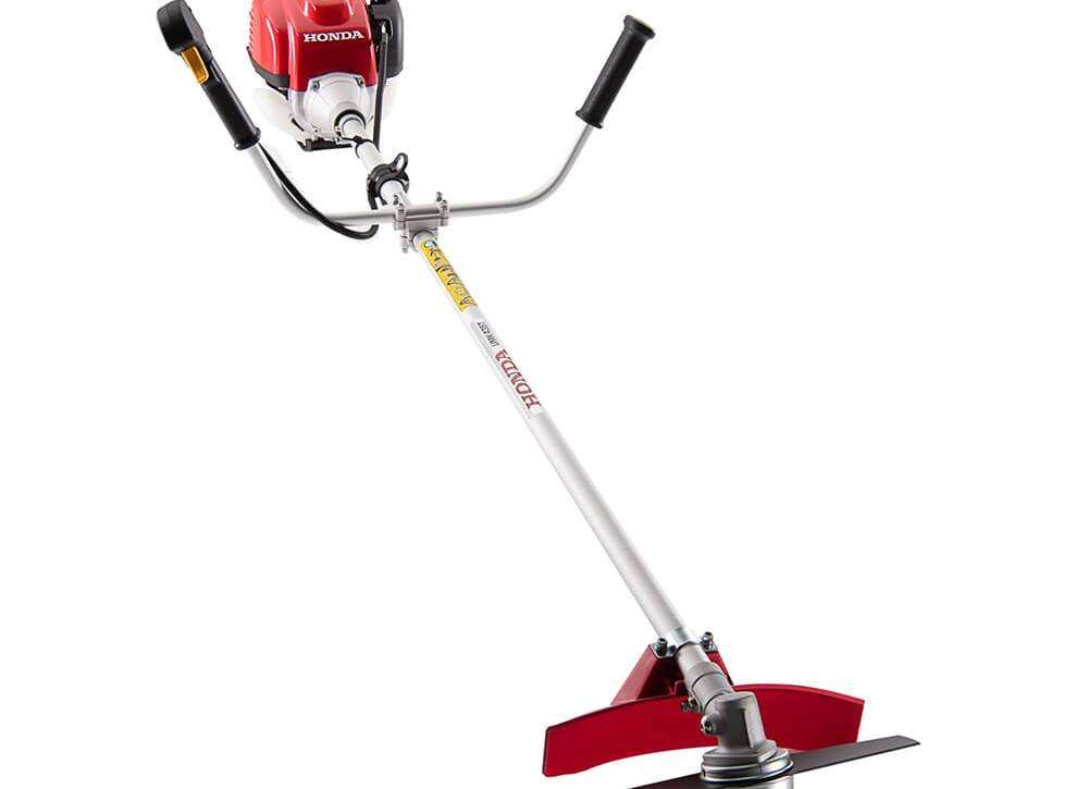 Honda UMK435 4-stroke grass cutting machine with bike handle standing on farm ground in Pakistan